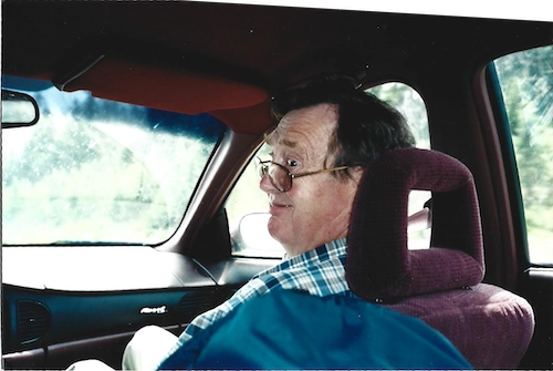 A picture of my dad looking back from the front seat of a car and making a funny face